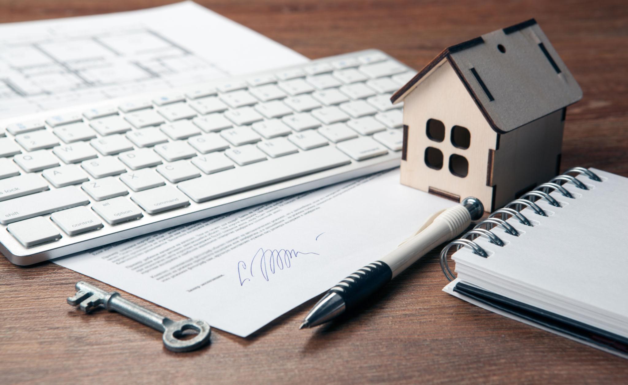 Home loan documents with house model and keys representing property financing and mortgage approval